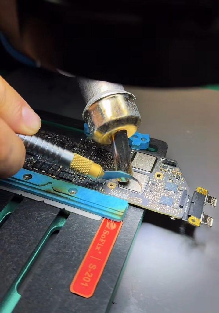 Técnico reparando un chip dañado en la placa base de un MacBook